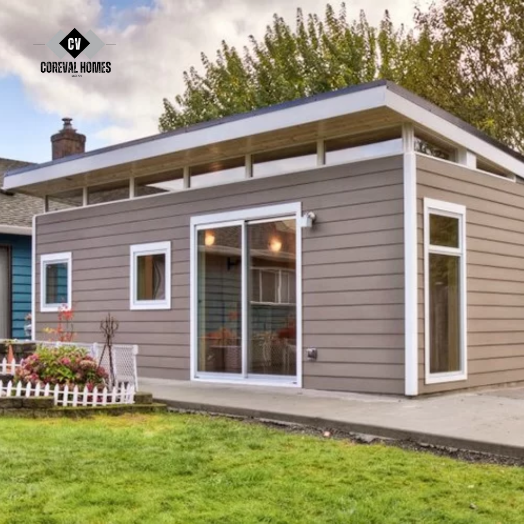 Compact modern laneway home in Vancouver with grey siding, flat roof, and white trim, set beside a small garden and lawn.